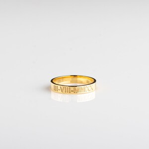 May include: A gold band ring with the inscription "III-VIII-MMXX" engraved on the outside.