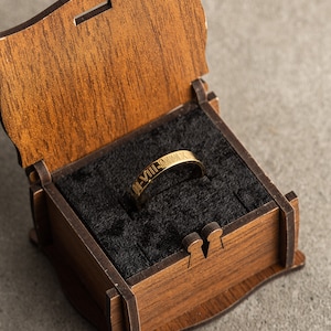 May include: A gold ring with Roman numerals engraved on it, inside a wooden box with a black velvet lining.