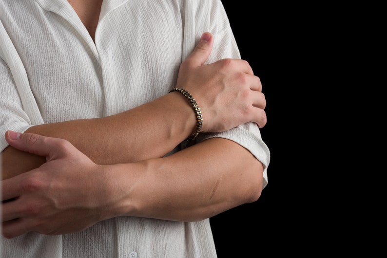 Men's bracelet with black hematite beads and gold-tone highlights, secured by an oxidized 925 sterling silver clasp and chain, offering adjustable sizing and a sleek design.