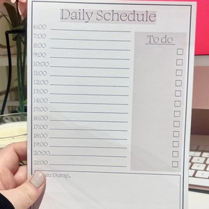 May include: A white daily schedule planner with a black border. The planner has a column for the time of day from 6:00 AM to 9:00 PM and a column for to-do items with checkboxes.