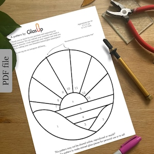 Op de afbeelding: Een zwart-wit printbaar patroon voor een zon en oceaan scène van glas-in-lood. Het patroon is verdeeld in 13 secties, genummerd van 1 tot 13. Het patroon is ongeveer 17 cm bij 17 cm.