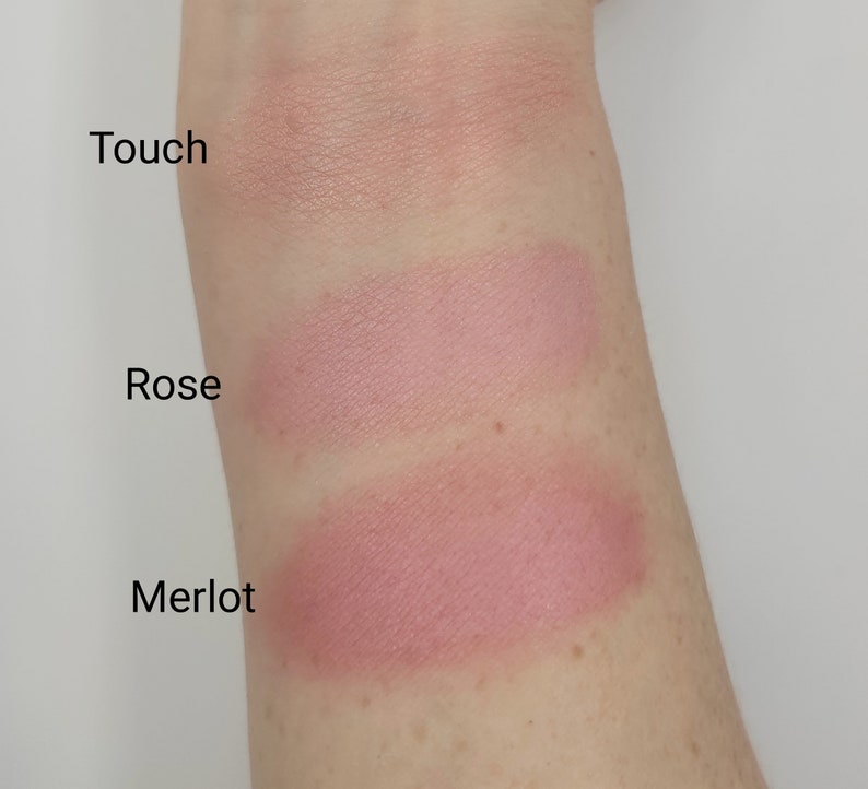 May include: Swatch of three blush colors on a person's arm. The colors are labeled "Touch", "Rose", and "Merlot".