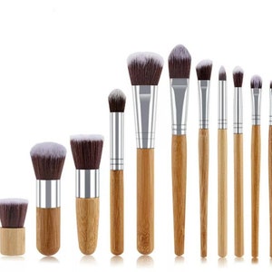 Peut inclure: Ensemble de 10 pinceaux de maquillage avec des manches en bambou et des viroles en métal argenté. Les pinceaux ont différentes tailles et formes pour diverses applications de maquillage.