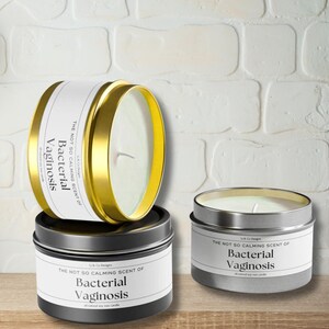 May include: Two soy wax candles in metal tins. The candles are labeled "The not so calming scent of Bacterial Vaginosis". One candle is gold and the other is silver.