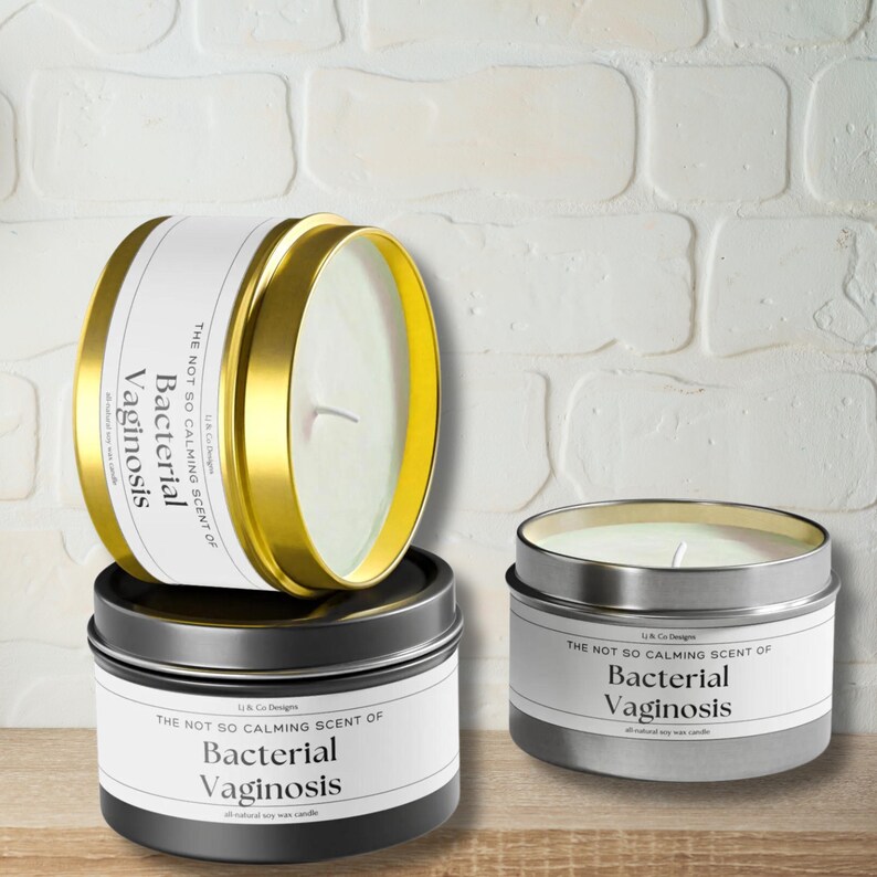 May include: Two soy wax candles in metal tins. The candles are labeled "The not so calming scent of Bacterial Vaginosis". One candle is gold and the other is silver.