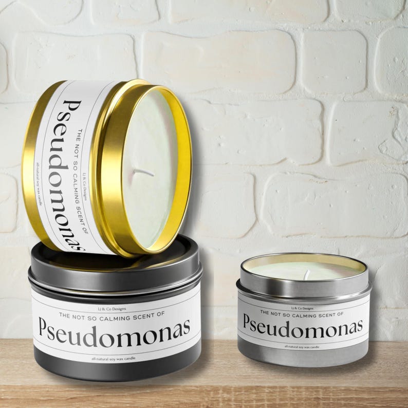 May include: Three candles in different sizes with gold and silver lids. The labels on the candles read "The not so calming scent of Pseudomonas".