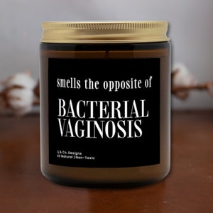 May include: A brown glass candle with a gold lid and a black label that reads "smells the opposite of BACTERIAL VAGINOSIS" and "Lj & Co. Designs All Natural | Non-Toxic".