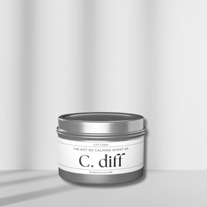 May include: A silver tin candle with a white label that reads "The not so calming scent of C. diff all-natural soy wax candle".