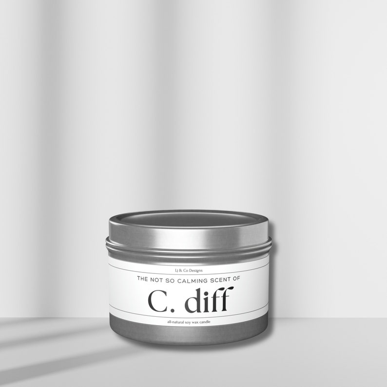 May include: A silver tin candle with a white label that reads "The not so calming scent of C. diff all-natural soy wax candle".