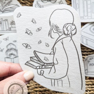 Puede incluir: Dibujo en blanco y negro de una persona leyendo un libro con mariposas volando a su alrededor. El dibujo está sobre un fondo blanco y tiene un aire fantasioso.