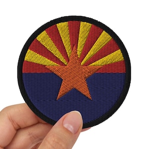 May include: A round embroidered patch featuring the Arizona state flag. The flag is red, yellow, and blue with a red star in the center.