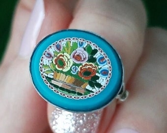 Puede incluir: Un anillo turquesa con un diseño de mosaico floral. El mosaico presenta una variedad de colores, incluyendo rosa, amarillo, naranja y verde.