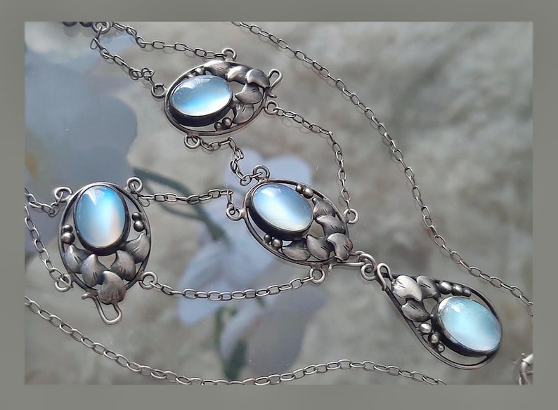 Puede incluir: Un collar de plata con cuatro colgantes ovalados de piedra lunar. Cada colgante est&aacute; engastado en un marco de plata con un dise&ntilde;o floral. El collar tiene una cadena delicada.