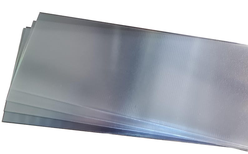 May include: A stack of clear, rectangular plastic sheets. The sheets have a slightly textured surface and are arranged in a neat pile. The edges of the sheets are visible, and the overall appearance is clean and simple.