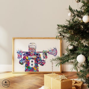 May include: A framed watercolor print of a lacrosse player in a colorful uniform, holding a lacrosse stick. The player's jersey has the number 8 and the word "NAME". The artwork is in a wooden frame, with a Christmas tree and wrapped gifts in the background.