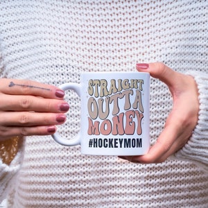 Hockey Mom 11oz Ceramic mug with graphic that says straight outta money, at the bottom it says hockey mom. This makes perfect hockey mom gifts for mothers day and a birthday, or to show your appreciation for your hockey mom, hockey coach or manager