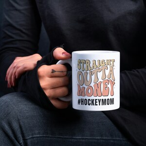 Hockey Mom 11oz Ceramic mug with graphic that says straight outta money, at the bottom it says hockey mom. This makes perfect hockey mom gifts for mothers day and a birthday, or to show your appreciation for your hockey mom, hockey coach or manager