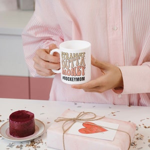 Hockey Mom 11oz Ceramic mug with graphic that says straight outta money, at the bottom it says hockey mom. This makes perfect hockey mom gifts for mothers day and a birthday, or to show your appreciation for your hockey mom, hockey coach or manager