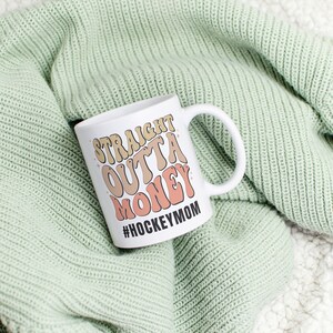 Hockey Mom 11oz Ceramic mug with graphic that says straight outta money, at the bottom it says hockey mom. This makes perfect hockey mom gifts for mothers day and a birthday, or to show your appreciation for your hockey mom, hockey coach or manager