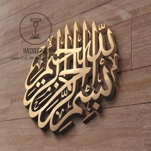 May include: A gold-coloured 3D wall decor featuring the Arabic calligraphy "Allah" in a decorative style. The calligraphy is mounted on a brown textured wall.