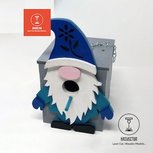 以下が含まれることがあります： 青、白、ピンク、黒の色合いで塗装された、ノームの形をした木製の鳥小屋。ノームは花の模様の青い帽子、白いひげ、ピンクの鼻をしています。鳥小屋はチェーンが付いた灰色の箱に取り付けられています。「HASVECTOR Laser Cut, Wooden Models...」の文字が見えます。