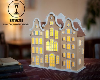 May include: A wooden model of a Dutch-style house with white trim and windows. The house is lit from within, creating a warm glow. The model is made by HASVECTOR, a company that specializes in laser-cut wooden models.