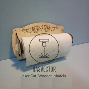 Puede incluir: Un porta rollo de papel de cocina de madera con un diseño decorativo y un rollo de papel de cocina. El soporte está montado en una pared y tiene un pequeño estante para guardar artículos. El texto "HASVECTOR Laser Cut. Wooden Models..." está impreso en el soporte.