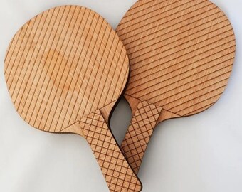 May include: Two wooden paddle rackets with a diagonal striped pattern. The rackets are made of light brown wood and have a natural finish.