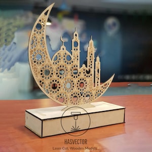May include: A wooden laser cut model of a mosque with a crescent moon. The model is on a wooden base and has intricate details. The text "HASVECTOR Laser Cut, Wooden Models..." is on the base.