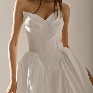 May include: A white strapless wedding dress with a fitted bodice and a flowing skirt.