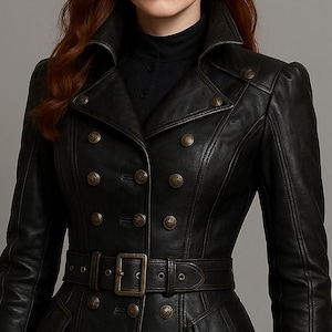 May include: Black leather coat with a double-breasted design, featuring multiple bronze-colored buttons and a matching belt. The coat has a tailored fit, long sleeves, and a flared skirt, creating a classic and elegant silhouette.