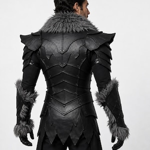 Puede incluir: Un chaleco de piel sint&eacute;tica negra con armadura de hombro superpuesta, cuello alto con ribete de piel sint&eacute;tica gris y guanteletes de antebrazo a juego con pu&ntilde;os de piel sint&eacute;tica gris. Dise&ntilde;o estructurado y segmentado con remaches y dobladillo.