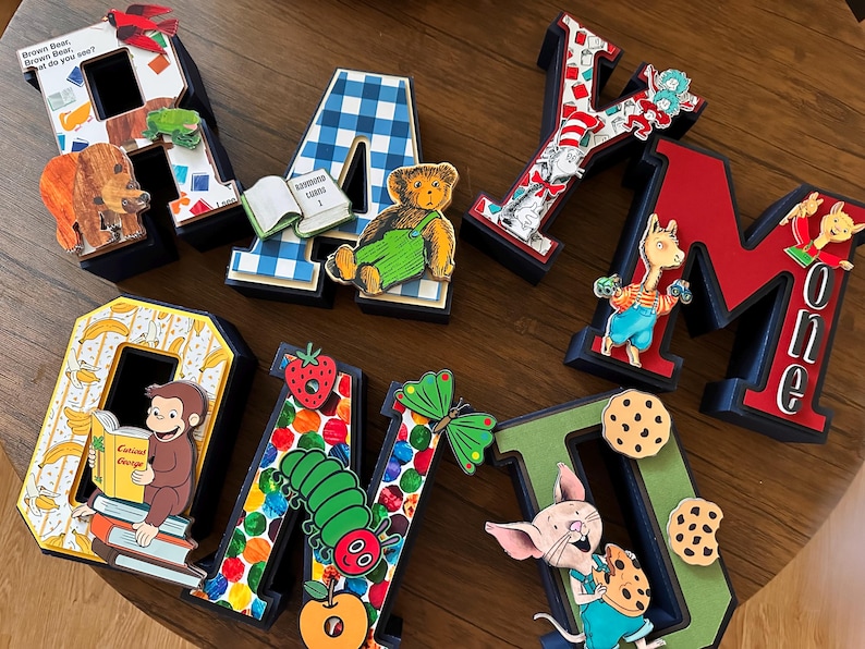 May include: A set of decorative 3D letters spelling RAYMOND, each featuring unique children's book character illustrations including a brown bear, a teddy bear, Curious George, a caterpillar, and a piglet, with colorful patterns and motifs.