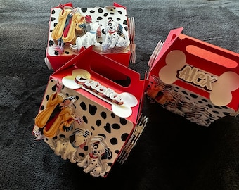 Könnte beinhalten: Drei rote und weiße Pappkartons mit Dalmatiner-Motiv. Die Kartons haben einen Griff und sind mit Dalmatinerflecken, einem Bild von Cruella de Vil und den Namen "Alex", "Isabella" und "Caella" verziert.