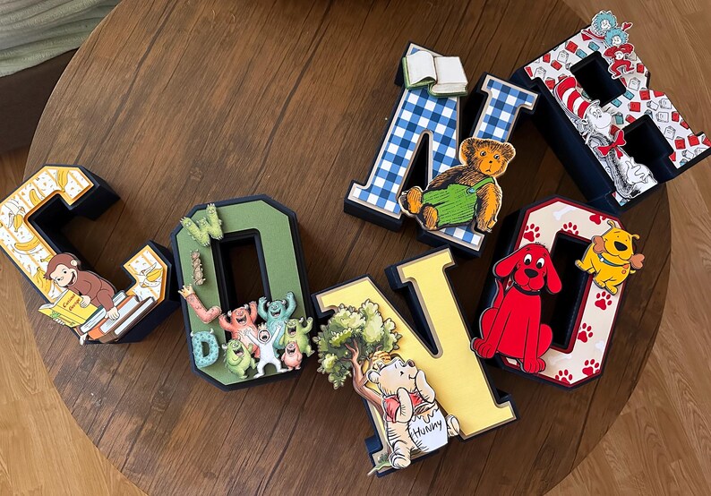 May include: A set of six three-dimensional letters spelling CONNOR, each decorated with various children's book characters and themes, including Curious George, Monsters Inc, Winnie the Pooh, The Cat in the Hat, and Clifford the Big Red Dog.