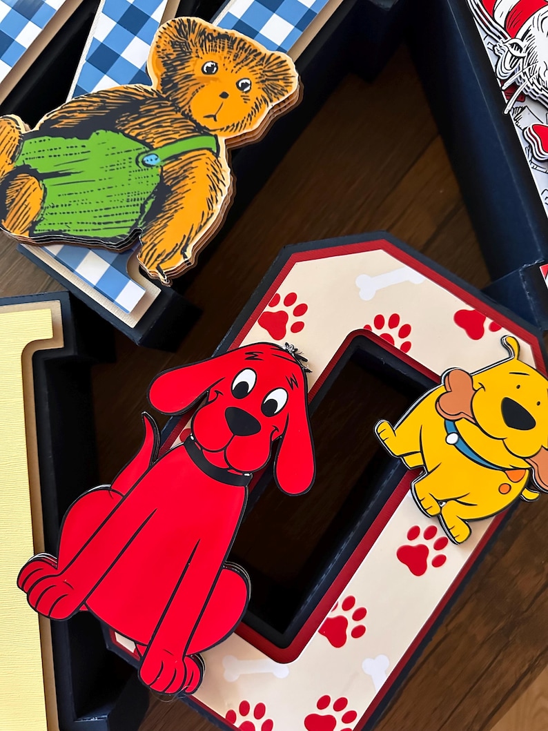 May include: A decorative letter O featuring a cream background with red paw prints and white bone patterns. A bright red dog character is attached to the left side, and a yellow dog character holding a bone is attached to the right side.