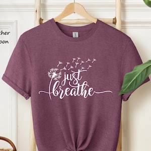 May include: Heather maroon t-shirt with a white dandelion graphic and the text "just breathe".