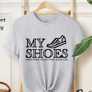 May include: A grey t-shirt with a black graphic of a running shoe and the text "My Shoes Have More Miles Than Your Car".