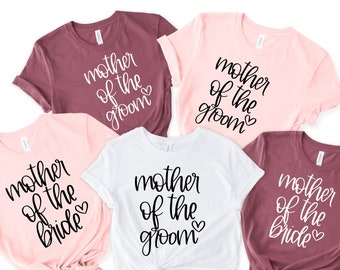 May include: Five t-shirts in different colors with the text "mother of the groom" or "mother of the bride" in black script.