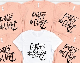 May include: Five peach-colored t-shirts with black text and a black anchor design. One white t-shirt with black text and a black anchor design. The text on the peach shirts reads "Party Crew". The text on the white shirt reads "Captain Bride".