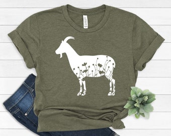 May include: A green t-shirt with a white silhouette of a goat with flowers inside the outline.