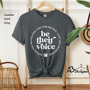 May include: Heather dark grey t-shirt with the text "be their voice" in a circular design. The design includes a paw print and the phrases "Rescue the mistreated, save the injured, love the abandoned."