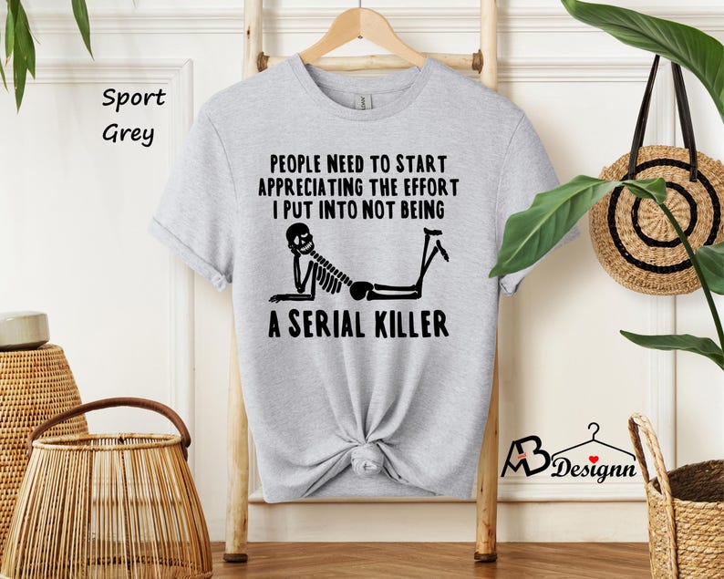 May include: A gray t-shirt with a black skeleton graphic and the text "PEOPLE NEED TO START APPRECIATING THE EFFORT I PUT INTO NOT BEING A SERIAL KILLER".