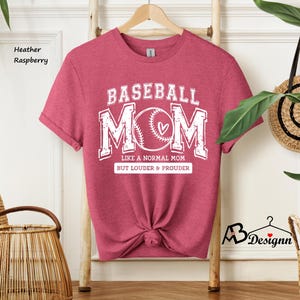 May include: Heather raspberry t-shirt with a white graphic that says "Baseball Mom" with a baseball and heart design. The text below the graphic says "Like a normal mom but louder & prouder".