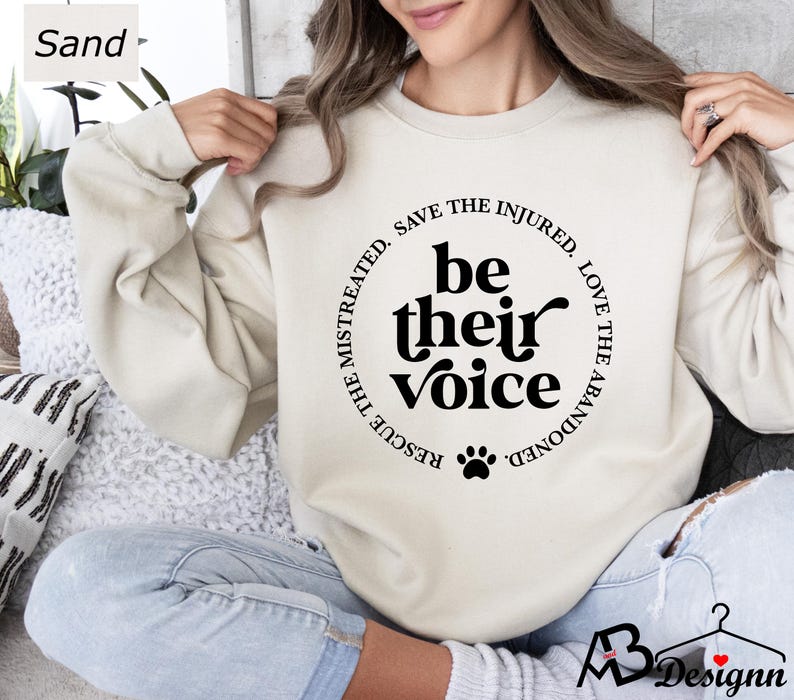 May include: A beige sweatshirt with a black paw print and the text "Rescue the mistreated, save the injured, love the abandoned. Be their voice." printed on the front.