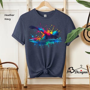 May include: A heather navy blue t-shirt with a colorful graphic of a swimmer in a splash of paint.