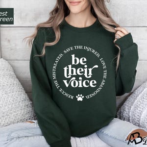 May include: A forest green sweatshirt with a white circle graphic that says "Rescue the mistreated, save the injured, love the abandoned, be their voice".