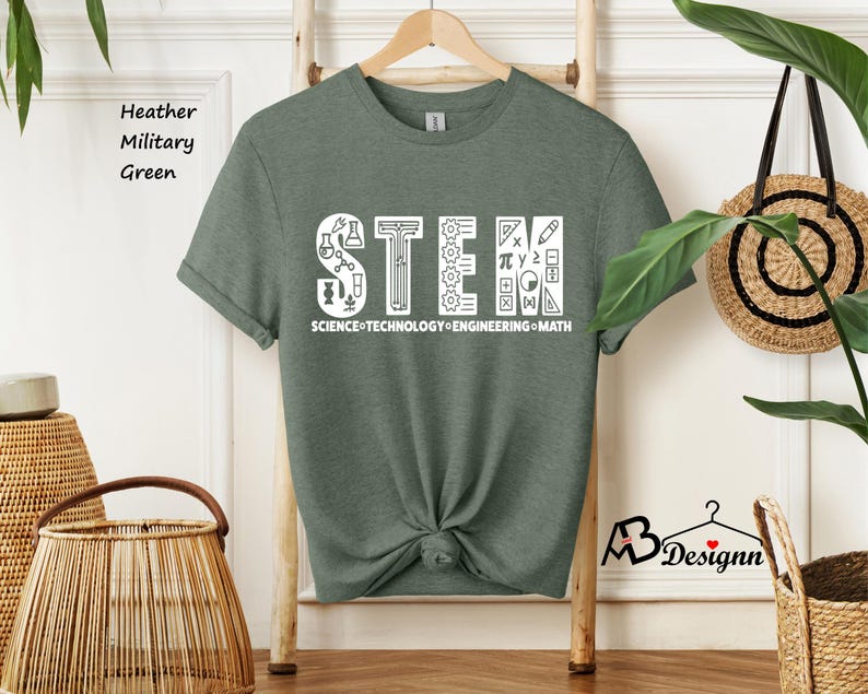 May include: A heather military green t-shirt with a white graphic of the word "STEM" made up of icons related to science, technology, engineering, and math. The text "SCIENCE TECHNOLOGY ENGINEERING MATH" is written below the graphic.