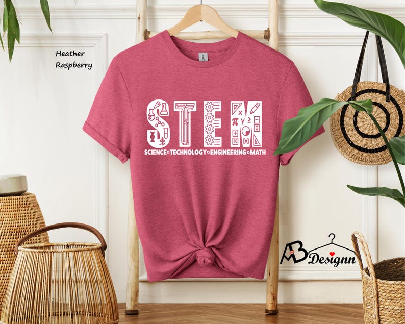 May include: Heather raspberry t-shirt with a white graphic that says "STEM" with icons representing science, technology, engineering, and math. The text below the graphic says "SCIENCE TECHNOLOGY ENGINEERING MATH".