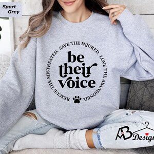 May include: A gray sweatshirt with a black paw print and the text "RESCUE THE MISTREATED. SAVE THE INJURED. LOVE THE ABANDONED. be their voice" printed on the front.